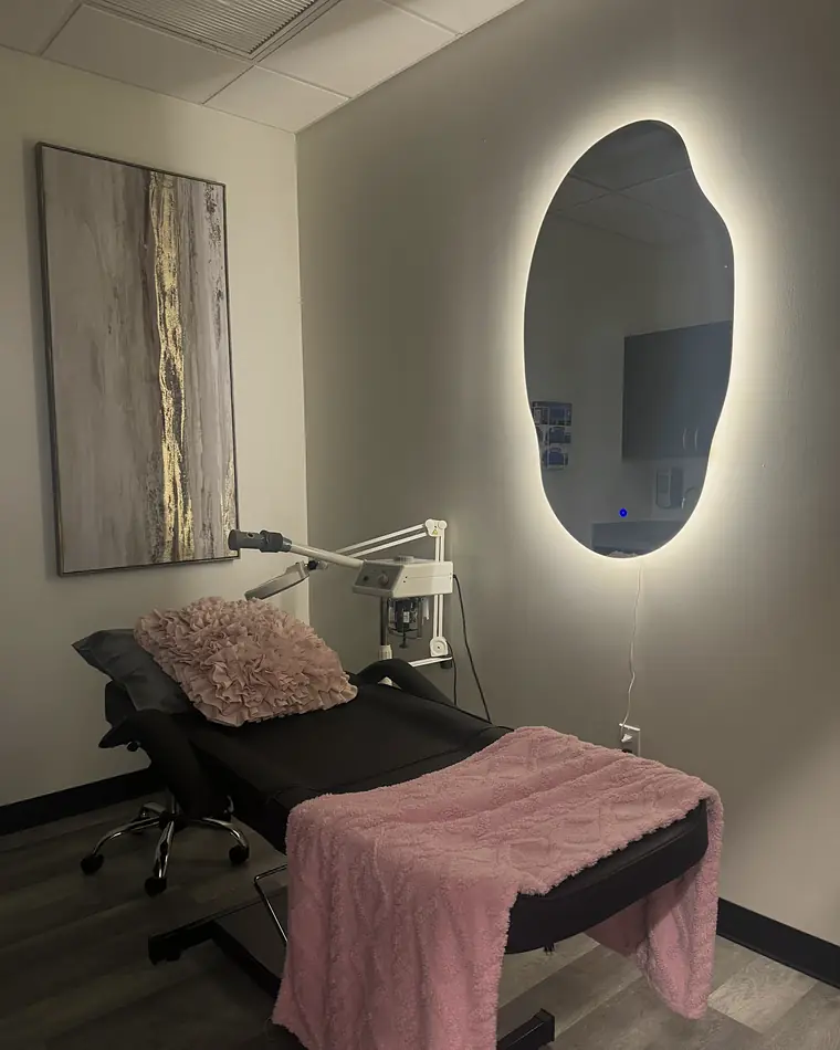 A PISO treatment room with a backlit mirror and a pink throw